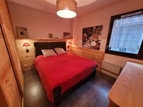 - une chambre avec un lit rouge et une grande fenêtre dans l'établissement Appartement cosy aux Gets, balcon et parking au centre - FR-1-598-184, aux Gets