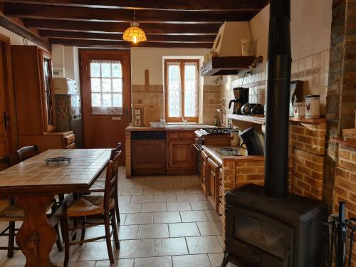une cuisine avec une cuisinière, une table en bois et une table ainsi qu'une salle à manger dans l'établissement Gîte calme avec jardin privé près forêt & Loire - FR-1-590-533, à Dampierre-en-Burly