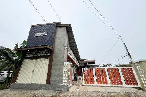 a house with white doors and a fence at RedDoorz Syariah at Hostel Imah 3 Lampung in Kedaton