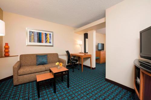 a hotel room with a couch and a table at Fairfield Inn & Suites by Marriott Bloomington in Bloomington