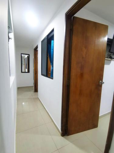 a hallway with a wooden door and white walls at Andaliving Campo Valdés in Medellín