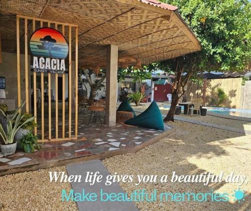 a sign for a beach resort with a swimming pool at Acacia Sunset Village Inn in Dauis