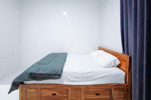 a bed with white sheets and a blue curtain at Widi Guest House near GWK Mitra RedDoorz in Jimbaran