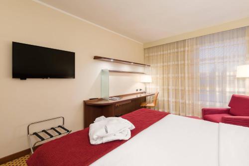 a hotel room with a bed and a red couch at Courtyard by Marriott Venice Airport in Tessera