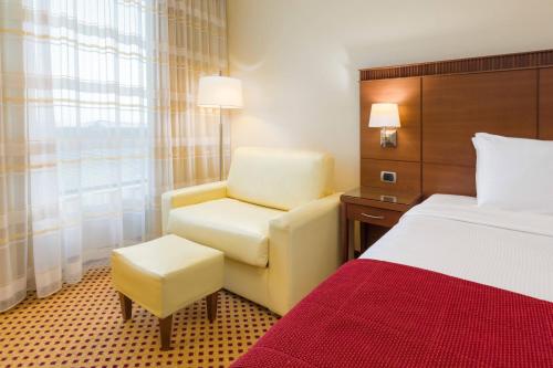 a hotel room with a bed and a chair at Courtyard by Marriott Venice Airport in Tessera