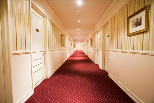 a long hallway with red carpeting and a long aisle at Redearth Boutique Hotel in Mount Isa