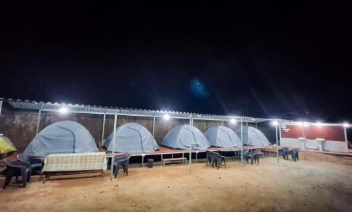 a group of tents in a field at night at The nest bettathur Coorg campsite in Madikeri
