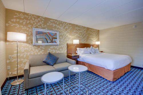 a hotel room with a bed and a couch at Fairfield Inn Boston Woburn in Woburn