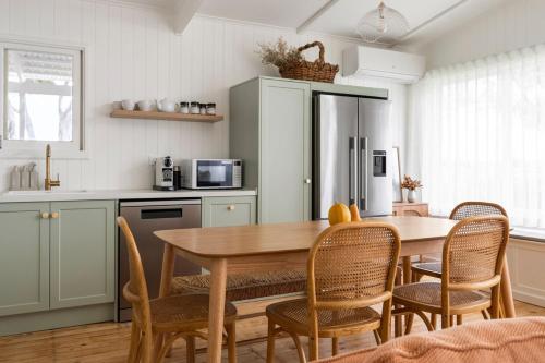 a kitchen with a table and chairs and a refrigerator at Wine Down McLaren Vale, a cosy vineyard retreat in McLaren Vale