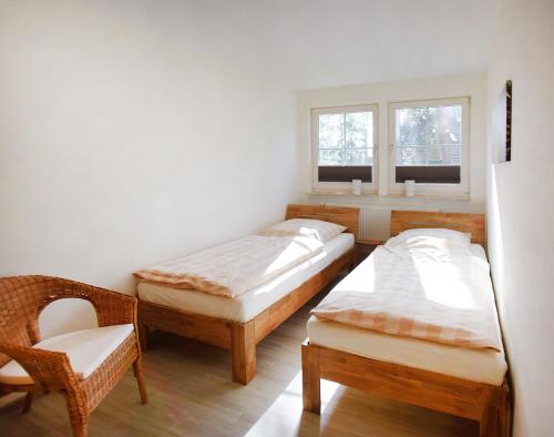two beds in a room with a chair and a window at Am Darßwald Haus 2 1 in Prerow