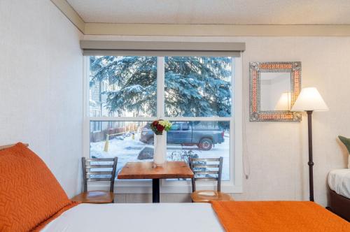 a room with a bed and a table with a vase of flowers at Mountainside Inn 304 by Alpine Lodging Telluride in Telluride
