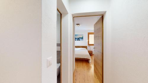 a hallway to a bedroom with a bed and a mirror at Abitaziun Pra d'Sura 133 - Maloja in Maloja