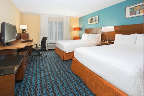 a hotel room with two beds and a desk and a television at Fairfield Inn & Suites by Marriott Boston Milford in Milford