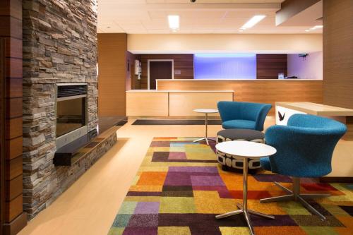 a lobby with a fireplace and blue chairs at Fairfield Inn & Suites by Marriott Boston Milford in Milford