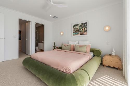 a bedroom with a large bed with a green ottoman at Sunsets Aldinga Beach, 4 king rooms, rooftop, incredible views in Aldinga Beach