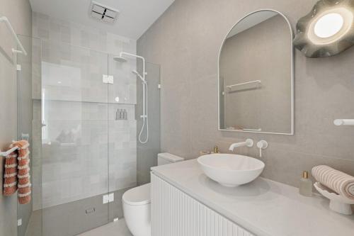 a bathroom with a sink and a toilet and a mirror at Sunsets Aldinga Beach, 4 king rooms, rooftop, incredible views in Aldinga Beach