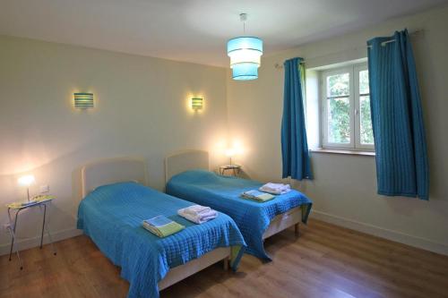 two beds in a room with blue sheets at La feuillardiere in Dournazac