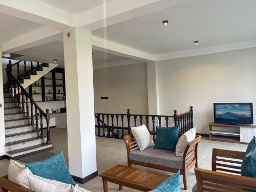 a living room with a couch and chairs and a staircase at Lush Breeze in Kandy