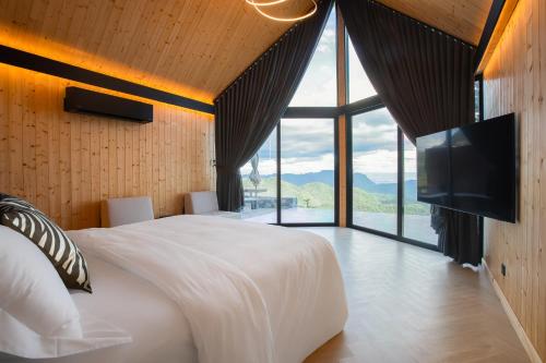 een slaapkamer met een groot wit bed en een groot raam bij The Pino Khao Kho in Phetchabun