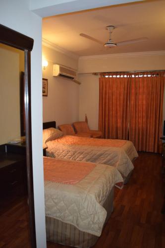 a hotel room with two beds and a couch at Carlton Tower Hotel Lahore in Lahore