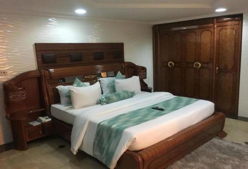 a bedroom with a large bed with a wooden headboard at Cynergy Suites Royale - Standard in Lagos