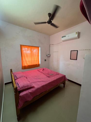 a bedroom with a bed with a red comforter and a window at Viky villa in Velānganni