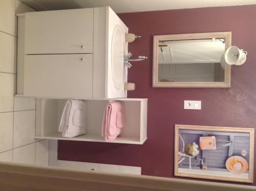 La salle de bains est pourvue d'une armoire blanche et d'un miroir. dans l'établissement Au Jardin D'Eloïse, à Tréméreuc