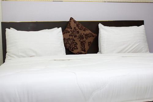 a bed with white sheets and pillows at Bristlecone Suites - Economy Double in Abuja