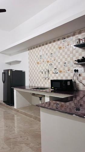 a kitchen with a black refrigerator and a counter at THE ELEGANT VILLA WITH KITCHEN, Opp to Mangrove Boating - JR Groups in Puducherry