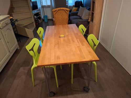 - une table en bois avec des chaises vertes dans la cuisine dans l'établissement Grain de sable ! terrasse en ville, à Le Touquet-Paris-Plage