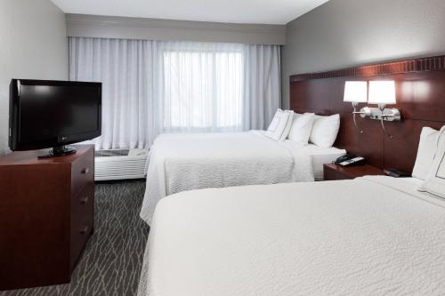 a hotel room with two beds and a flat screen tv at Courtyard by Marriott Waco in Waco