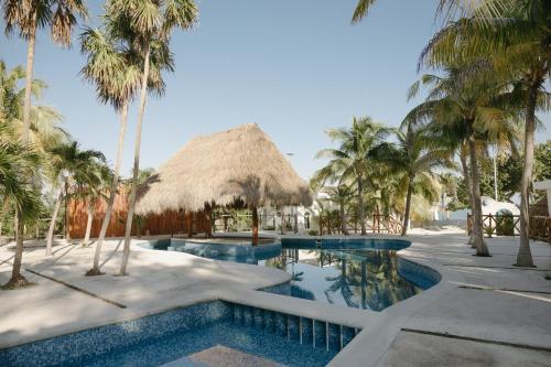 a resort swimming pool with palm trees and a thatchedilion at Elysian Private Haven Ultimate Front Beach Paradise, Isla Blanca in Isla Blanca