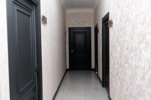 an empty corridor with black doors and a tile floor at Samarkand Hostel in Samarkand