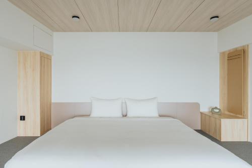 a bedroom with a large white bed and wooden ceilings at Adagio Dapeng Bay in Donggang