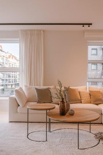 a living room with a white couch and two tables at Huswell - Luxury apartment with parking in Knokke in Knokke-Heist