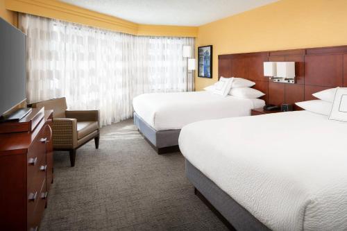 a hotel room with two beds and a chair at Courtyard by Marriott Fishermans Wharf in San Francisco
