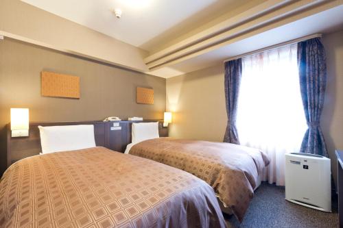 札幌市にあるホテルサンルート札幌のベッド2台と窓が備わるホテルルームです。