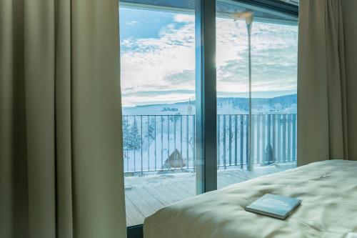 a book on a bed in front of a window at Summit of Saxony Resort Oberwiesenthal in Kurort Oberwiesenthal