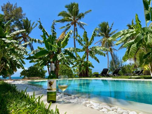 a bottle of wine and glasses next to a swimming pool at Luxury Lions Villas Zanzibar - with Private Cook&Infinity Pools in Kiwengwa