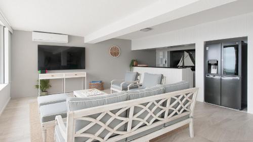 a living room with a table and chairs and a kitchen at Seaside Sanctuary - Waterfront Luxury Home with Heated Pool in Salamander Bay