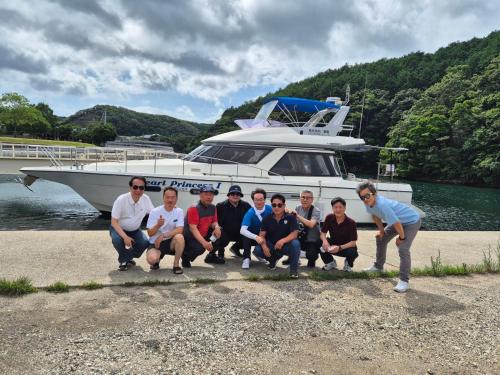 a group of people posing in front of a boat at 대마도쇼핑구마에하우스 in Tsushima