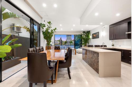 a kitchen and dining room with a wooden table and chairs at 3 m Luxury Waterfront Villa in Paradise Pets Welcome in Gold Coast
