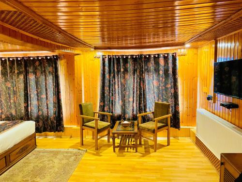 a bedroom with a bed and two chairs and a table at Marina Drung Waterfall By Stay Pattern in Gulmarg