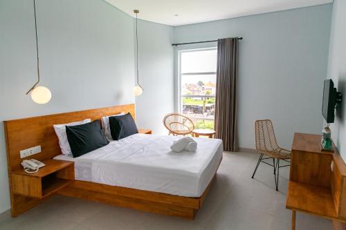 a bedroom with a bed and a desk and a television at Coco & Pineapple Pants Hostel in Canggu