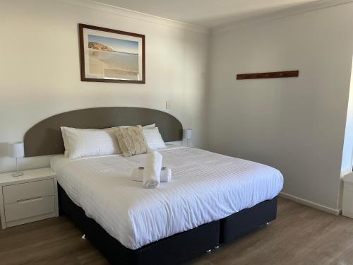 a bedroom with a bed with two towels on it at Clearwater Motel Apartments in Esperance