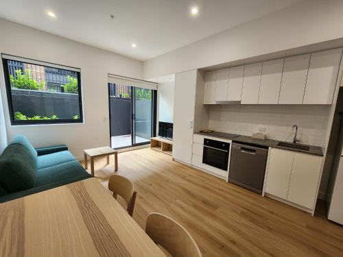 a kitchen and living room with a table and a blue couch at Discover Kingsford in Sydney