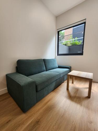a living room with a green couch and a table at Discover Kingsford in Sydney