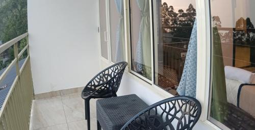 a balcony with two chairs and a window at Sky Elanza in Munnar