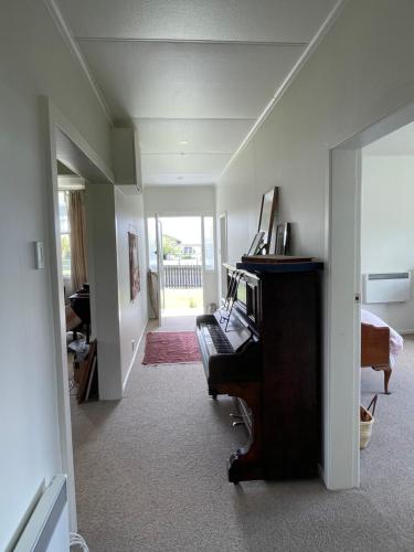 un salon avec un piano et une chambre avec un couloir dans l'établissement Seamstress Cottage, à Marton