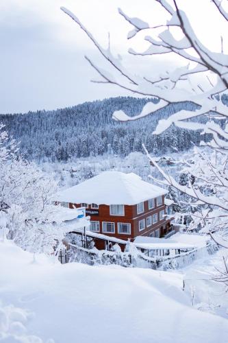 a building covered in snow with trees in the background at Marina Drung Waterfall By Stay Pattern in Gulmarg
